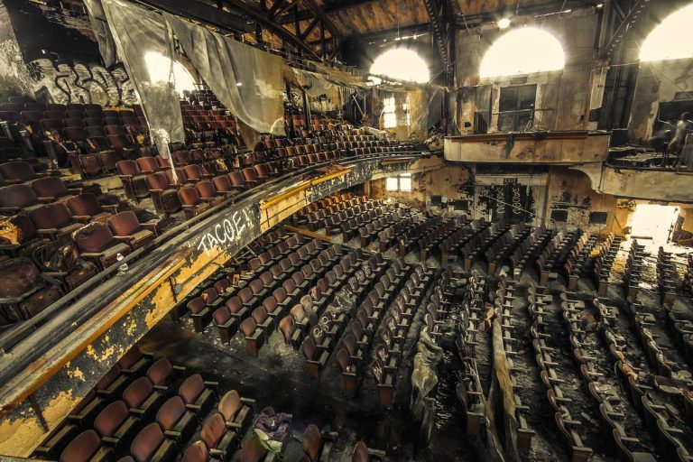 Abandoned theater auditorium with decayed seating and stage area